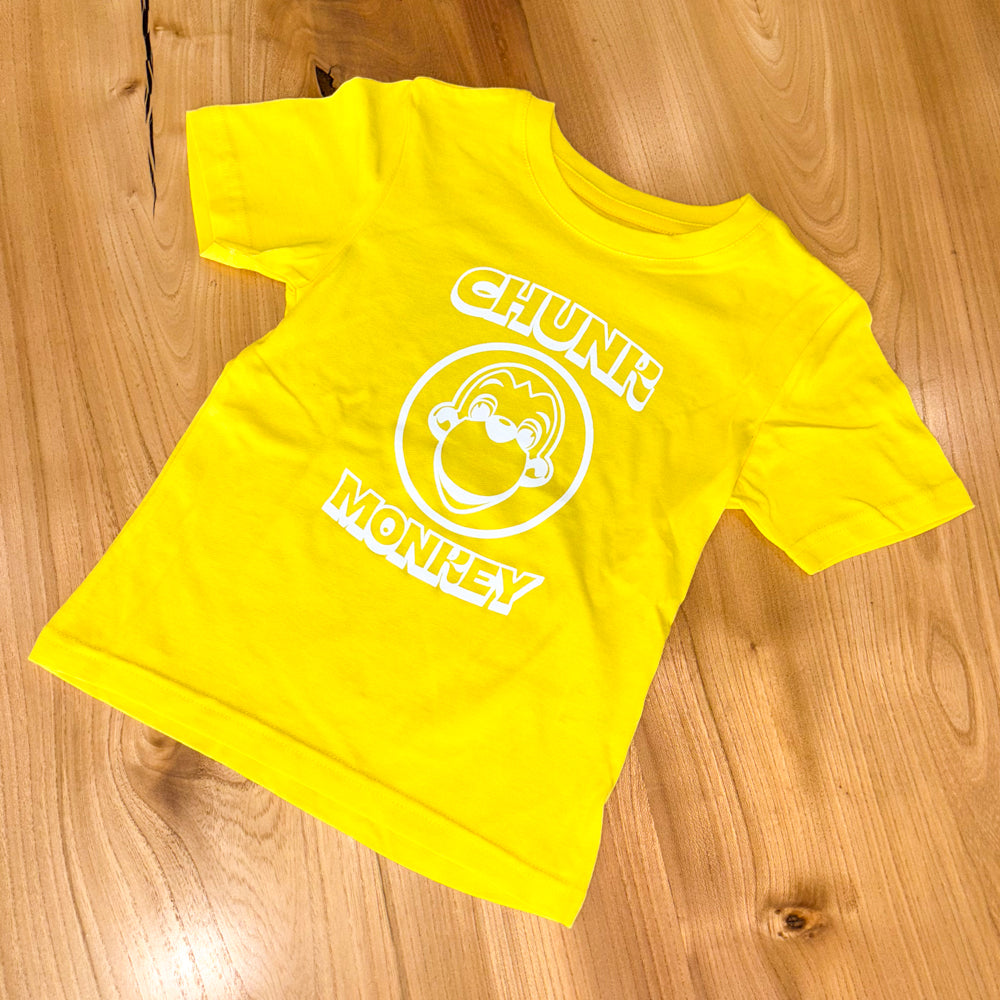 Yellow t-shirt with 'Chunk Monkey' logo on a wooden surface