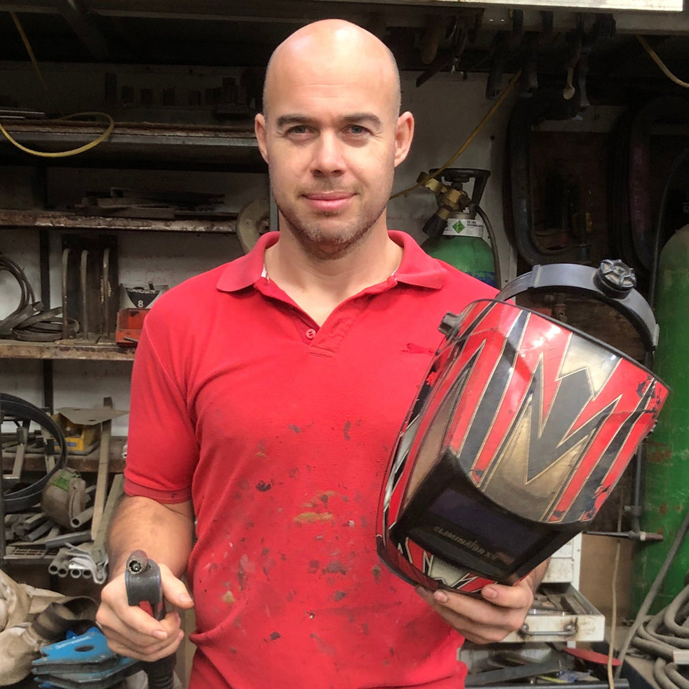 Chunk Monkey founder, owner and fabricator Dan Faull holding a welding helmet in the Swansea workshop.