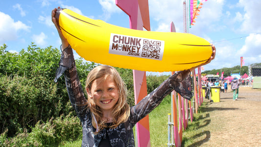 A happy girl proudly holding an inflatable Chunk Monkey banana above her head at In It Together Festival