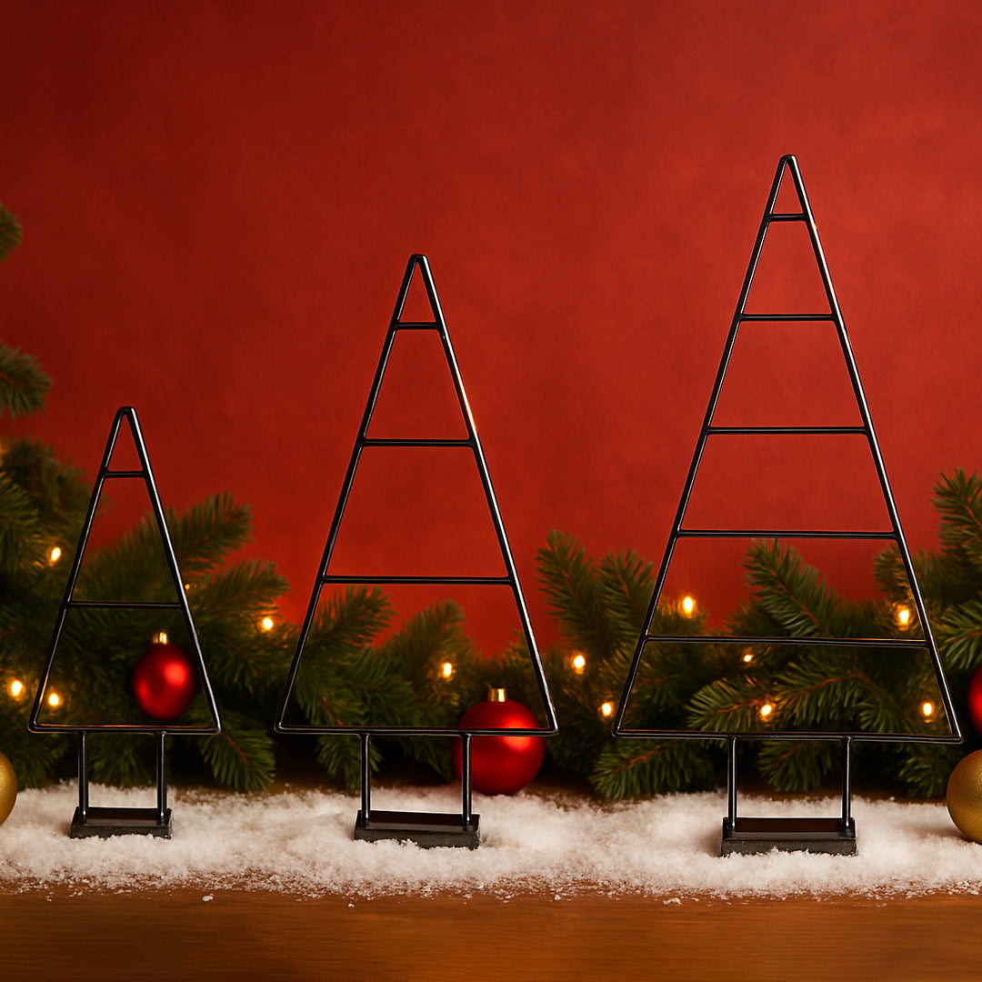 Three black metal Christmas tree stands with red ornaments on a snowy ground against a red background.