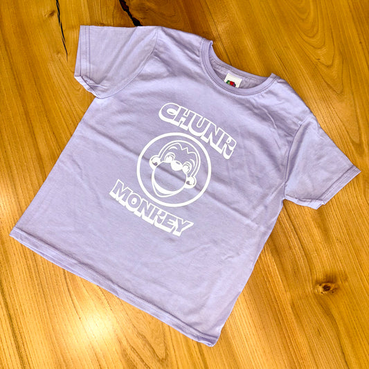 Lilac t-shirt with 'Chunk Monkey' design on a wooden surface