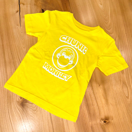 Yellow t-shirt with 'Chunk Monkey' logo on a wooden surface
