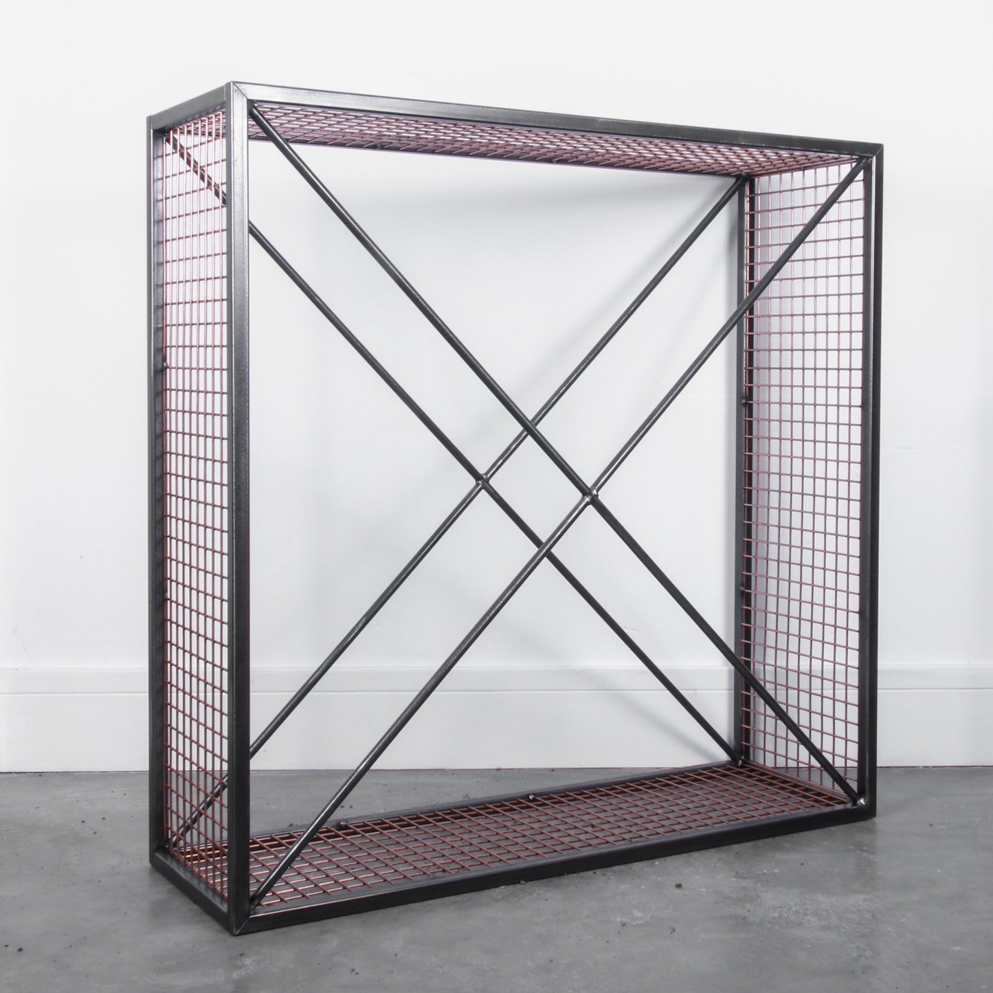 Side angle of an empty metal firewood holder against a white background