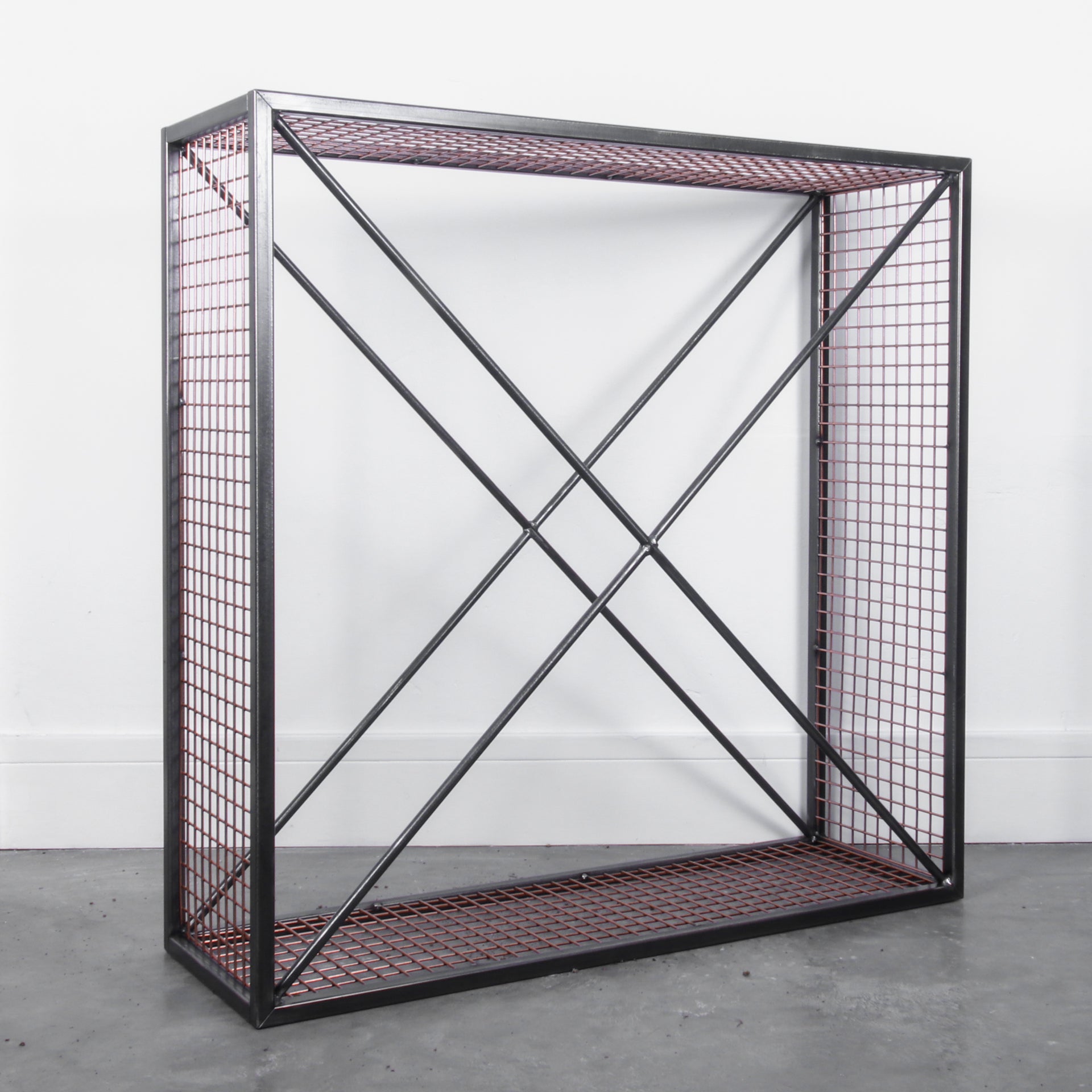 Side angle of an empty metal firewood holder against a white background